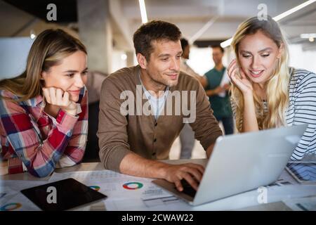 Young architect colleagues are analyzing blueprints while working on a new project Stock Photo