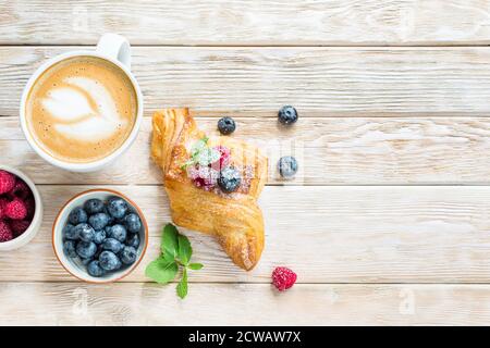 Puff pastry cake with berries and delicious cappuccino on a white wooden background. View from above. Place for text Stock Photo