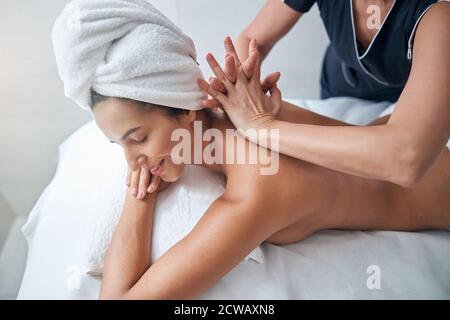 Charming young woman enjoying back massage in spa salon Stock Photo