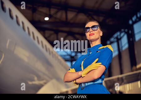 Successful female air hostess wearing respective blue uniform standing in the outdoors Stock Photo