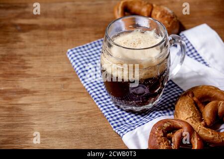 Glass of lager beer with traditional salted pretzels on white and blue napkin over wooden background. Oktoberfest theme Stock Photo