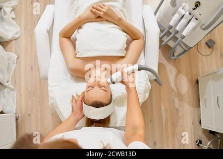woman close up receiving electric facial massage on microdermabrasion equipment at beauty salon. Stock Photo
