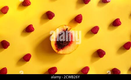 Raspberries and peaches for healthy summer eating - on yellow background Stock Photo
