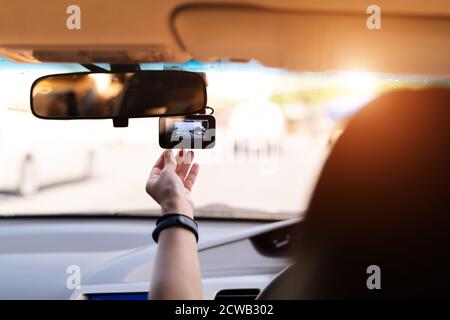 Front camera car recorder, woman set video recorder next to a rear view mirror Stock Photo