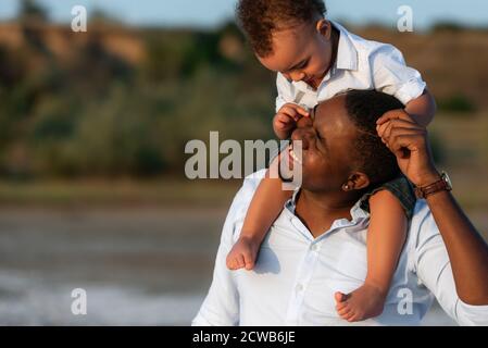 Dad and little son are having fun, fooling around together. Happiness and smiles around. Handsome young Afro American father and his cute son Stock Photo