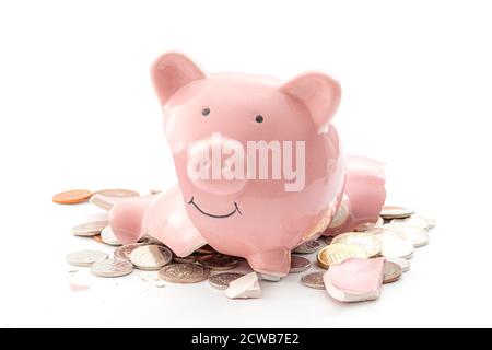 Break the bank, economic downturn and bankruptcy concept theme with a broken piggy bank and scattered coins isolated on white background Stock Photo