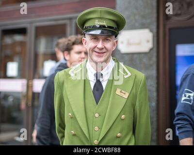 Street Photography: Portrait of Harrods Department Store Receptionist with Green Uniform and Hat in London. Stock Photo