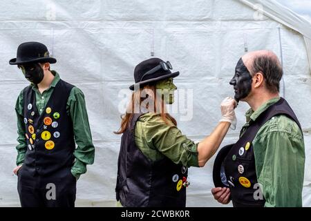 A Group Of Morris Dancers Applying Their Make Up Prior To Performing At The Hartfield Village Fete, Hartfield, East Sussex, UK. Stock Photo