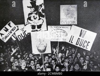 Black and white photo of the a large crowd in Milan showing enthusiasm for the announced mobilization for the invasion of Ethiopia; they hold placards in honour of Mussolini and in favour of the invasion. Stock Photo