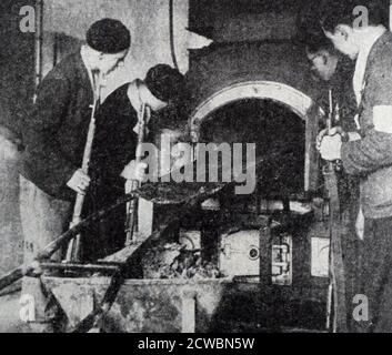 Black and white photograph of World War II (1939-1945) showing the German Concentration Camps at Buchenwald and Struthof; four Allied soldiers inspect one of the ovens used to cremate the remains of executed prisoners. Stock Photo