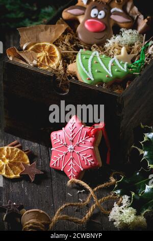 Christmas Handmade patterned gingerbreads as Christmas tree, reindeer Rudolph and snowflake shapes in wooden box over old wooden table, decorated by h Stock Photo