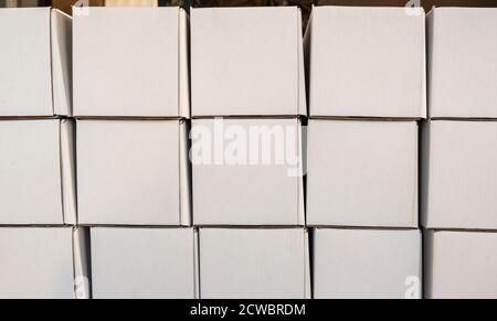Side view of white paper boxes in rows, minimalistic design objects. Wall with cardboard square shaped empty packages in delivery room, closeup view, Stock Photo