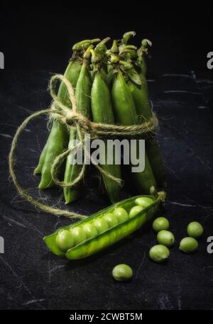 A bundle of fresh Peas on black marble Stock Photo