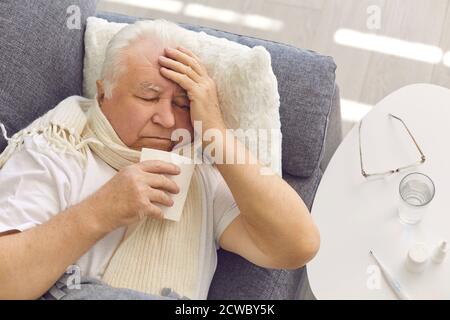 Senior man suffering from cold, flu or covid fever, coughing and having runny nose Stock Photo