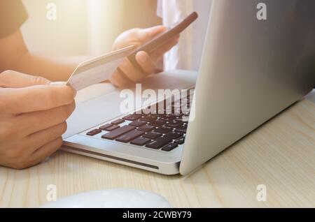 Man Shopping Online Using Laptop With Credit Card.Hands holding credit card and smartphone. Stock Photo