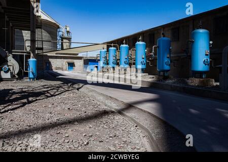 Jambyl Cement plant. Water purification and filtration station. Blue water filter tanks with valves and pipes. Round concrete silo and blue sky on bac Stock Photo