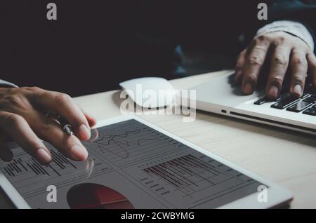Businessman analyzing graphs and charts report profit and growth statistics in tablets. Stock Photo