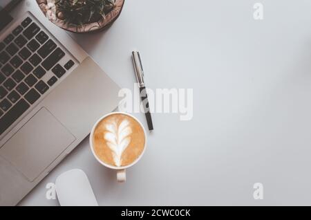 Office desk with keyboard, computer,pen, coffee and mouse on gray vintage tone background.Top view with copy space. Business and finance concept.flat Stock Photo