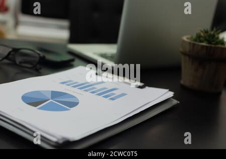 business documents, reports, graphs and charts of financial computer laptop on desk. Stock Photo