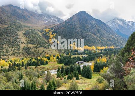 Mountain landscape view in Kyrgyzstan. Rocks, yellow and green trees in mountain valley view. Fall mountain panorama. Stock Photo