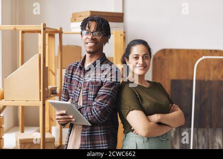 Portrait of two colleagues standing with arms crossed back to back and smiling at camera they working in delivery service Stock Photo