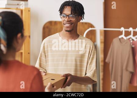 African young man giving the package to the woman and she delivering it to the customer Stock Photo