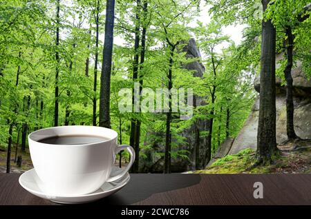 Cup of black coffee on wooden table with view of green forest, tree and natural view background Stock Photo