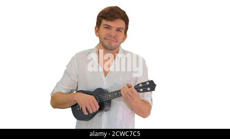 Smiling young man playing ukulele looking into the camera on whi Stock Photo