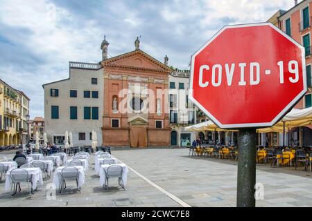 COVID-19 sign with view of empty cafes and restaurants in Italy. Warning about pandemic in Italy. Coronavirus disease. COVID-19 alert sign Stock Photo