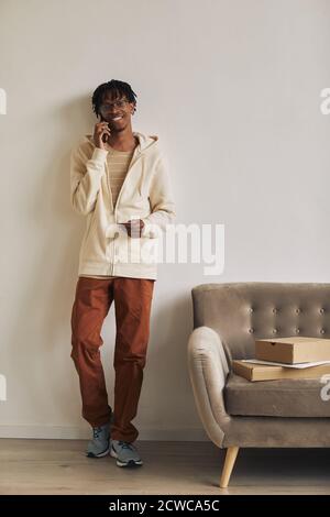 Smiling African man talking on mobile phone he preparing packages for delivery Stock Photo