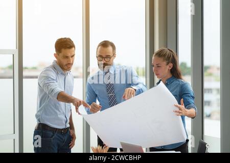 Team of multiethnic architects working on construction plans in meeting room. Engineers discussing on project in office. Stock Photo