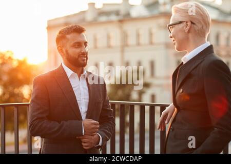 Business colleagues in elegant black suits talking to each other while standing on balcony Stock Photo