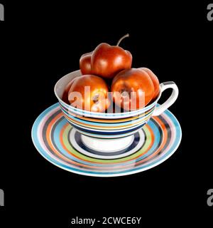 apples are beautifully stacked in a multi-colored cup on a saucer. Stock Photo