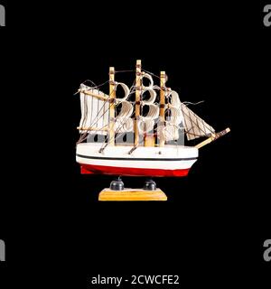 Toy boat sailboat on a wooden stand isolated on a black background Stock Photo
