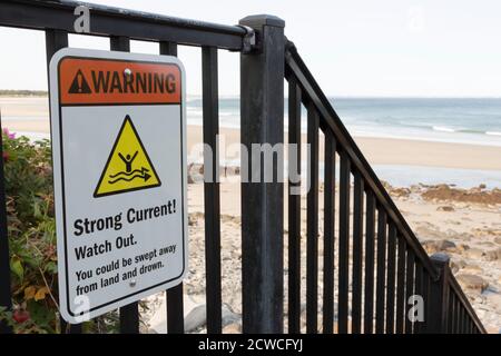 Sign warning beach goers and surfers about strong ocean current. Stock Photo