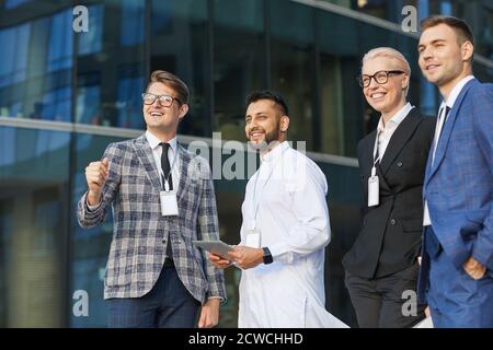 Successful business people looking away and smiling while standing in the city Stock Photo
