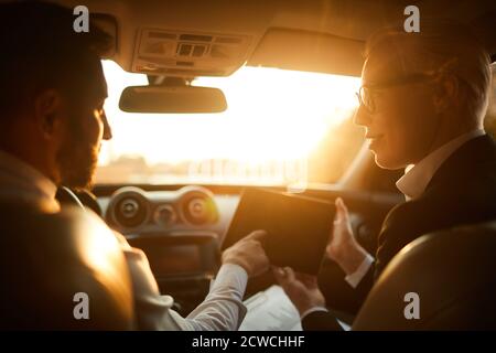 Rear view of business people using digital tablet and discussing online project sitting in the car Stock Photo