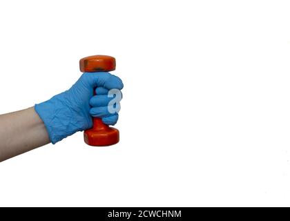 Hand in a blue nitrile surgical gloves holding a small dumbbell isolated on a white background Stock Photo