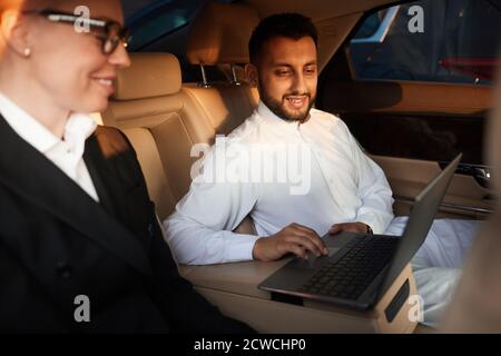 Business people sitting in the car and using laptop together during driving Stock Photo