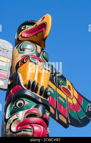 Colourful wooden carved Canadian totem pole showing eagle against blue sky Stock Photo