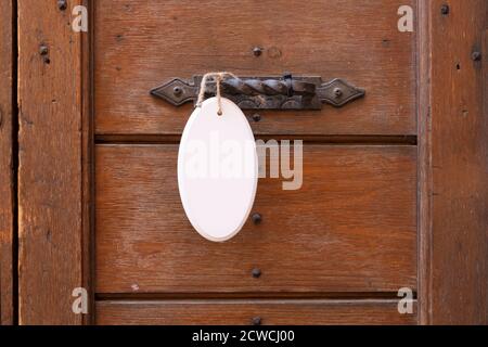 Antique door handle on a wooden door with a white sign hanging on a door Stock Photo