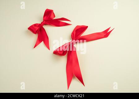 Red satin bows on a light beige background. Stock Photo
