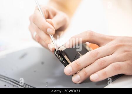 Master disassembles modern mobile phone, repairs and replaces battery, broken screen Stock Photo