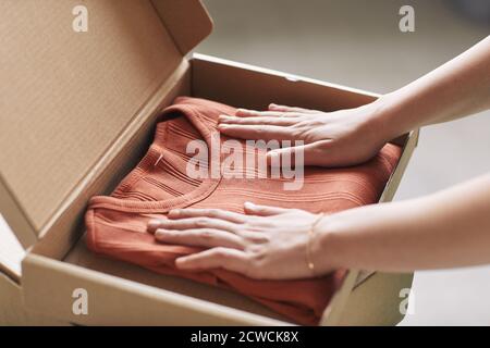 Close-up of woman opening parcel with new red shirt she getting her online order Stock Photo