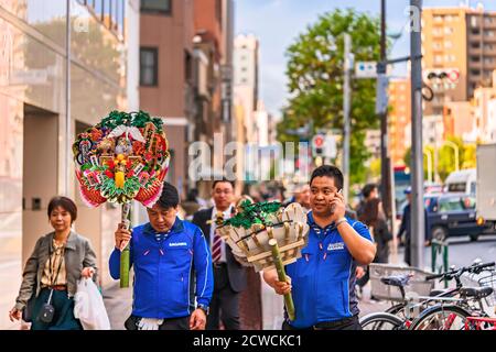 akihabara, japan - november 08 2019: Two traders back from the Tori-no-Ichi Fair at Shinto Ootori shrine where they bought two Engi Kumade or auspicio Stock Photo