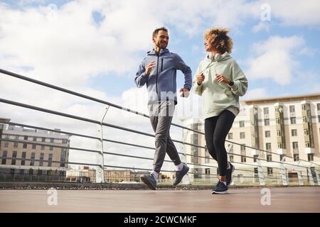 Young couple in sports clothing jogging together on the city street Stock Photo