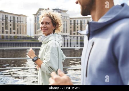 Young woman looking at her boyfriend and smiling during their jogging in the city Stock Photo