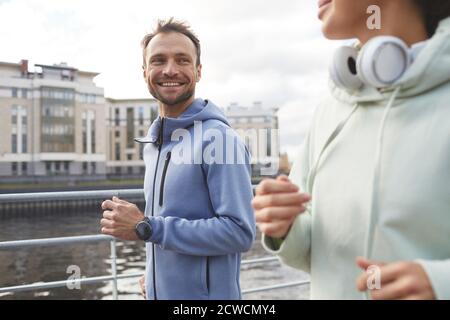 Happy young man smiling to his girlfriend while they jogging together in the city Stock Photo