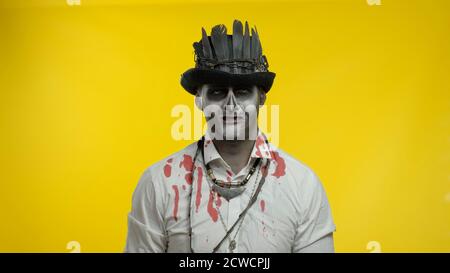 Creepy man with horrible Halloween skeleton makeup in costume with top-hat looking disappointed, upset, sad and crying. Horror theme. Day of The Dead. Isolated on black background Stock Photo