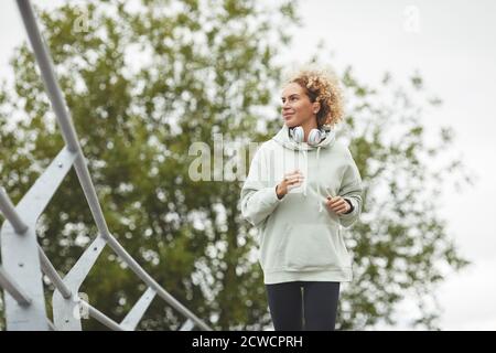 Young woman with curly hair jogging alone in the park outdoors Stock Photo